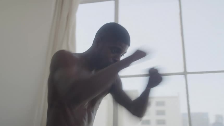 The man is shadowboxing in front of the mirror