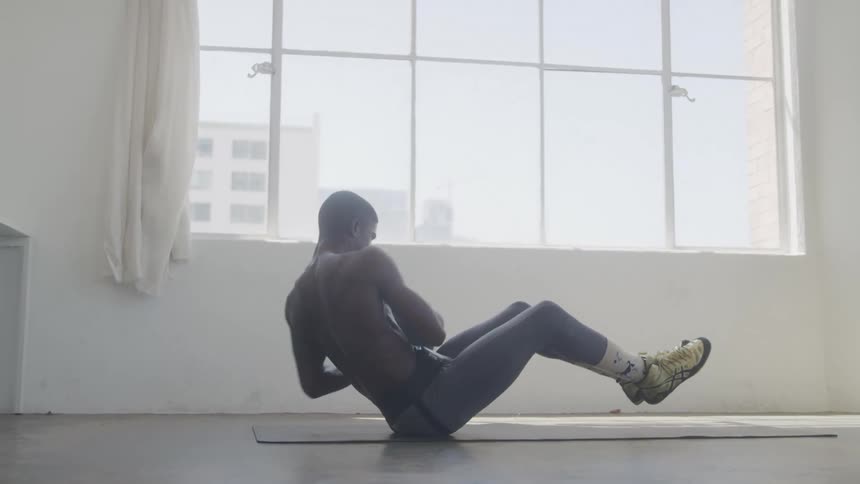 Shirtless man holding a ball and doing abdominal exercises