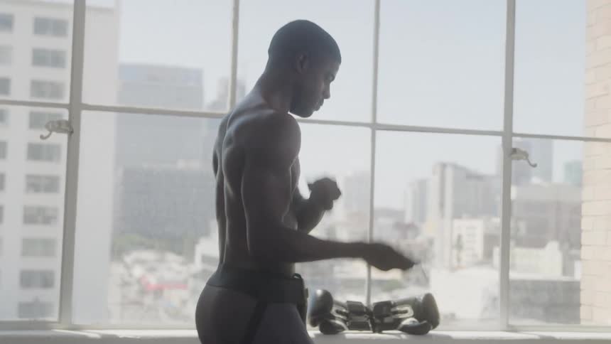 Shirtless man jumping rope indoors