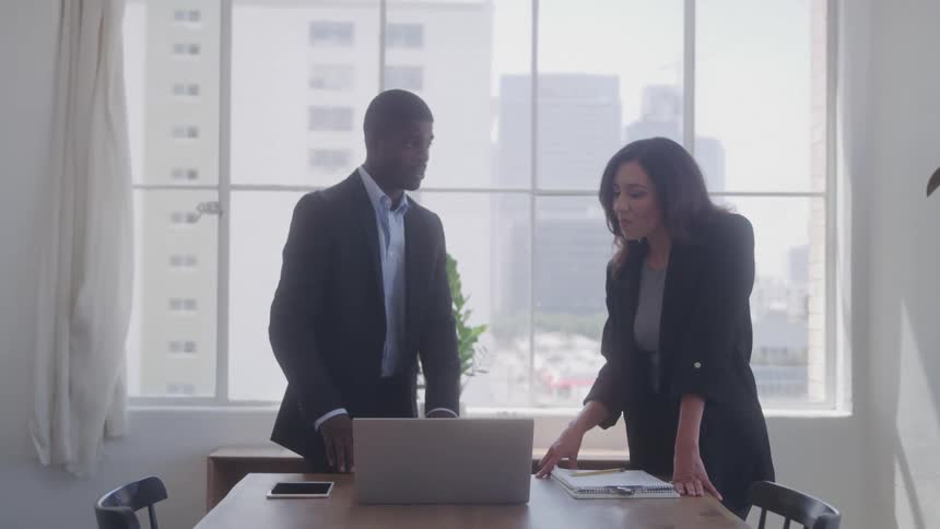 A man and woman discuss something they are looking at on the laptop