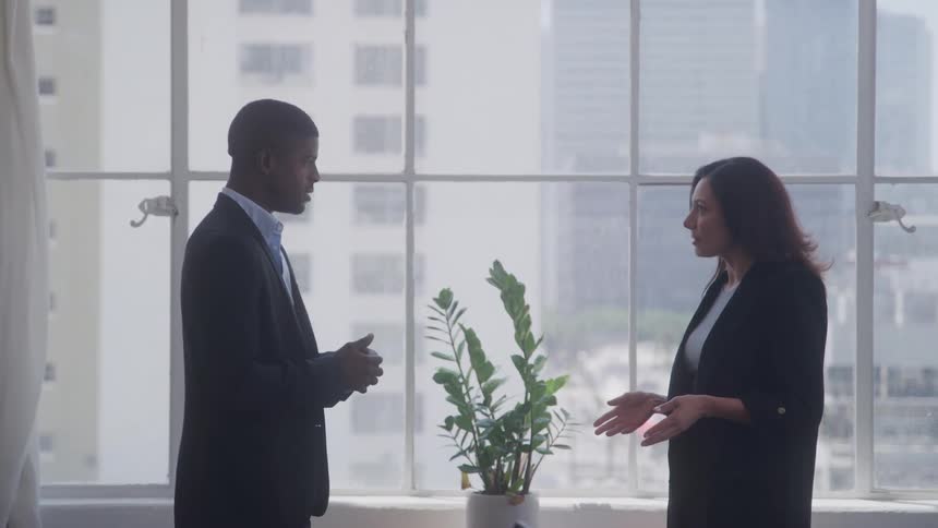 By the window in the office two coworkers talk
