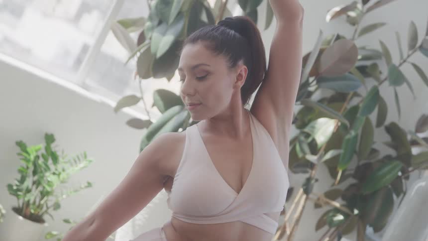 A woman is standing and holding a yoga pose with her arm in the air