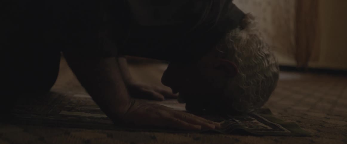 A man is praying in a dark room