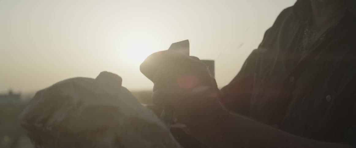 Man chiseling a sculpture outdoors as sun sets