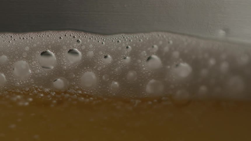 Extereme close up foamy beer bubbles rising to the top
