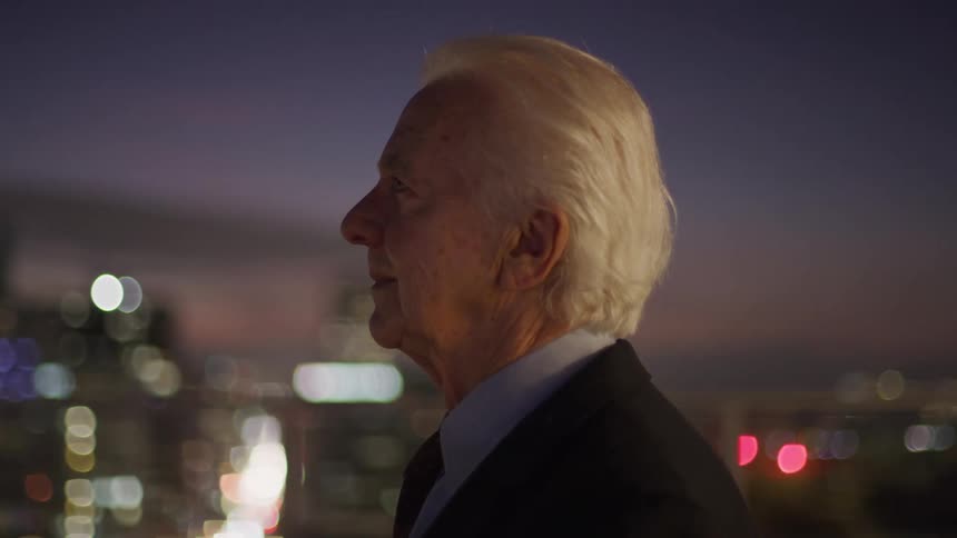 A man is looking at the city from a balcony