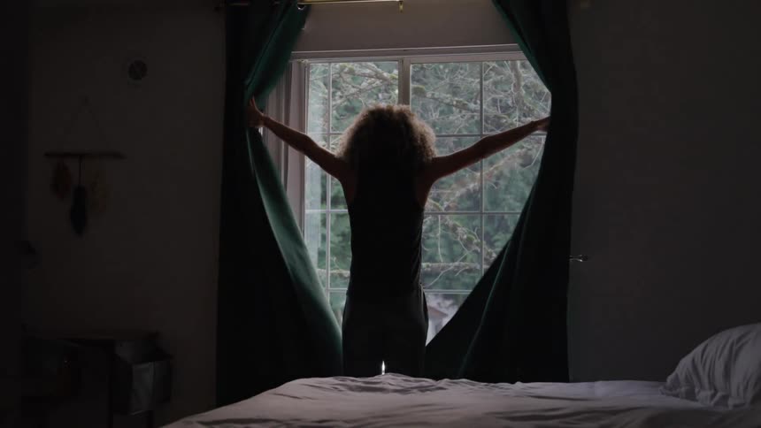 Girl opening the curtain of her room