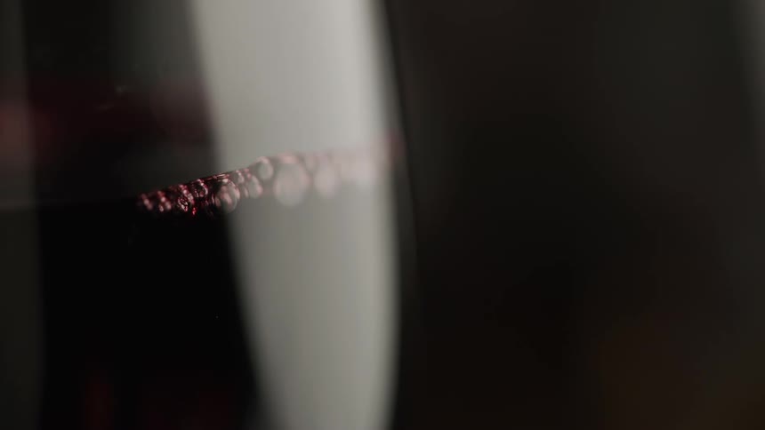 Bubbles form on the surface of a dark liquid inside a glass