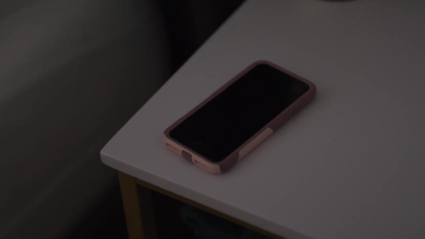 A smartphone on top of a desk ringing with the screen turning on and off