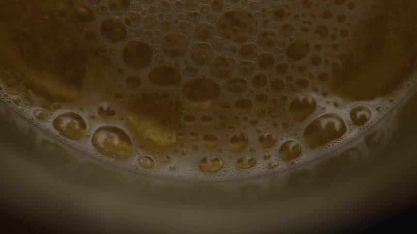 Beer is poured into a glass with foam on the surface