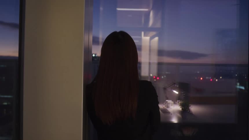 The woman leans against the window looking out