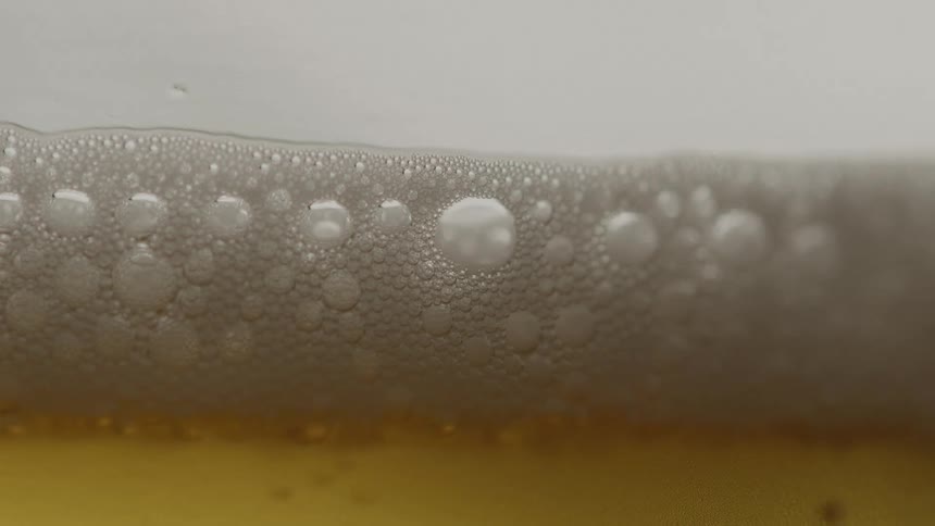 Tiny bubbles rising up from beer to join the foamy head