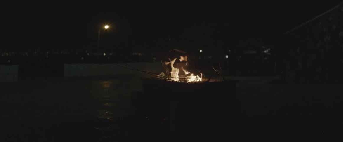 A pile of twigs is burning in a box at night