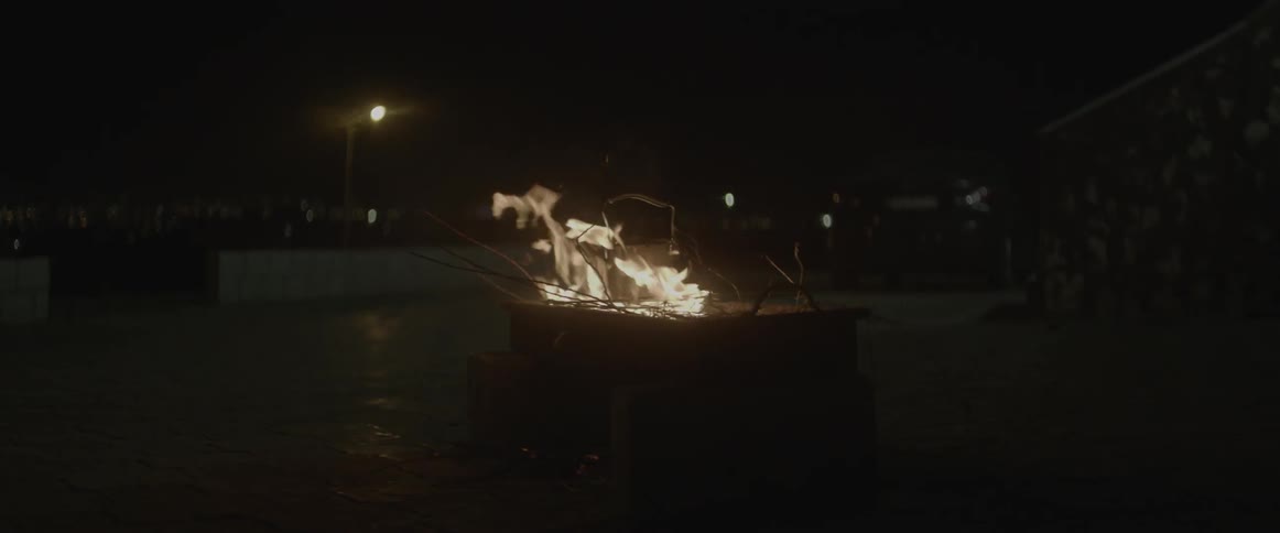 A fire burns outside at night
