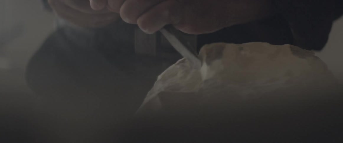 A man chips away at a chunk of wood with a chisel