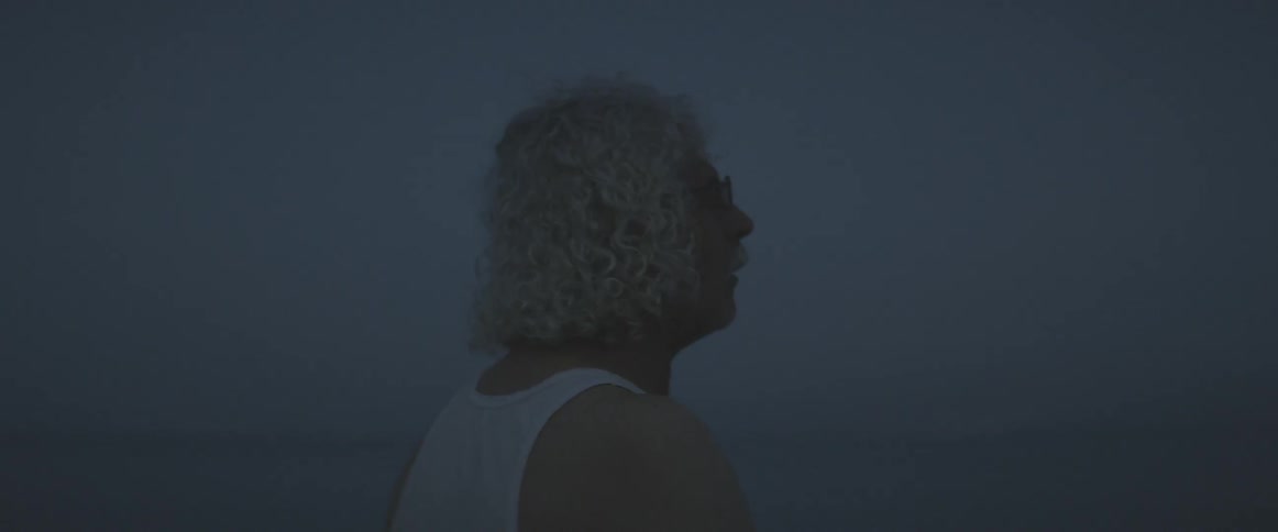 An elderly man wades out into water