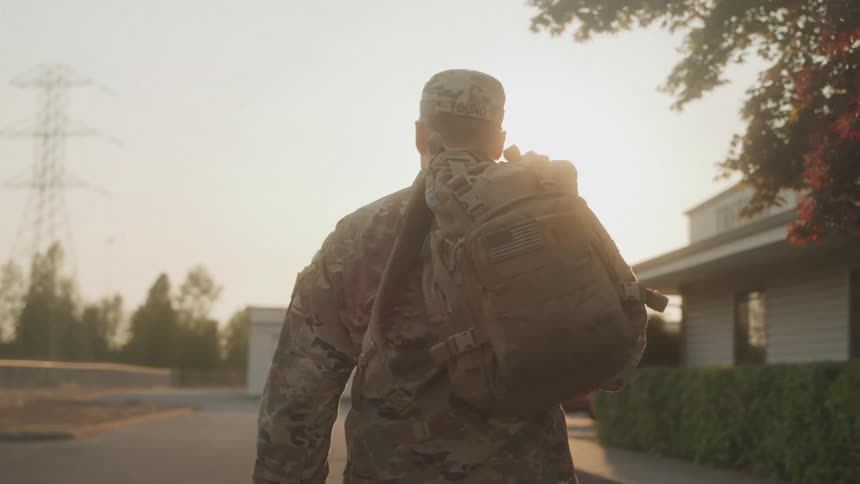 A soldier carries his backpack past the shops