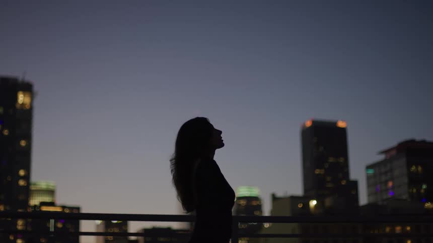 A woman looks up at the sky on the balcony
