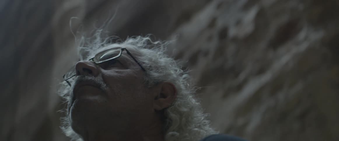 An older man is looking up at ruins and stone walls