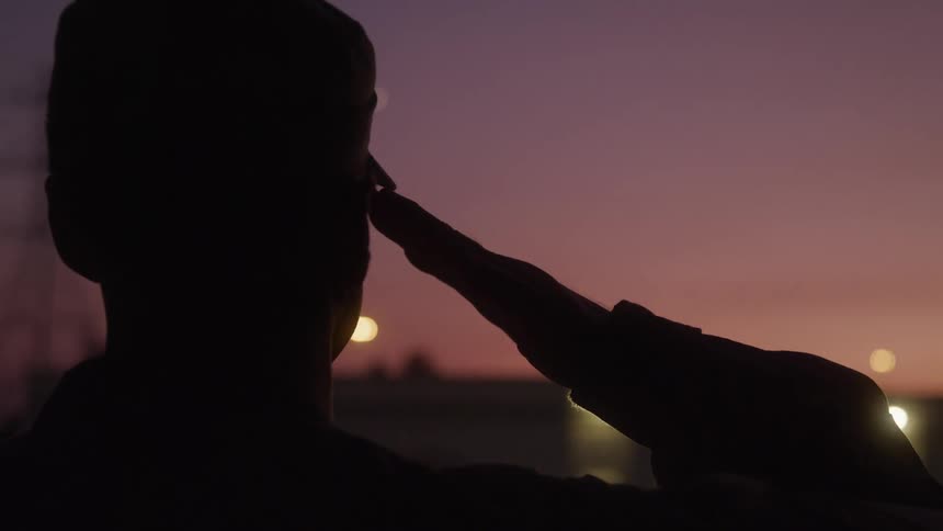 A military personnel saluting his superior outdoors in the evening