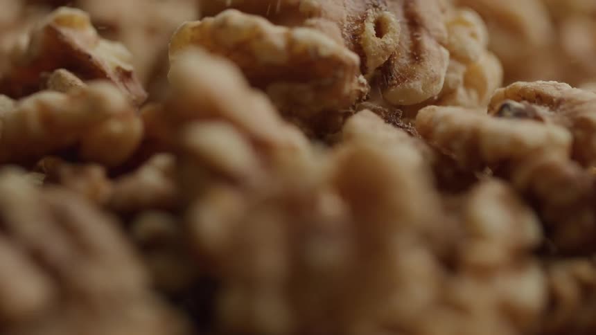 Walnuts falling onto a surface with many walnuts