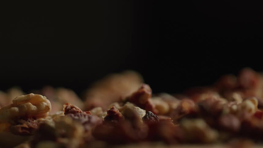 A shallow pile of walnuts is softly lit against a dark background