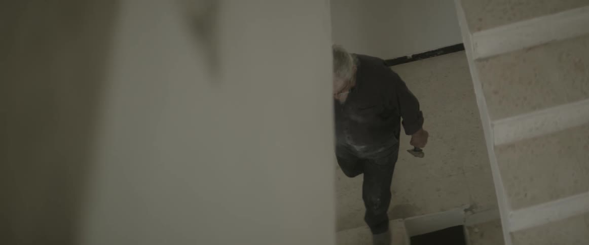 A man climbs the stairs holding a tool