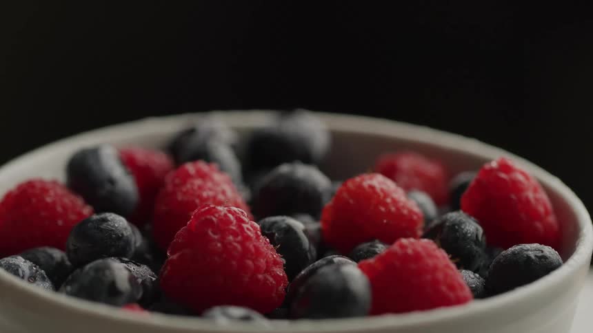 Fresh ripe raspberries and blueberries in a white bowl