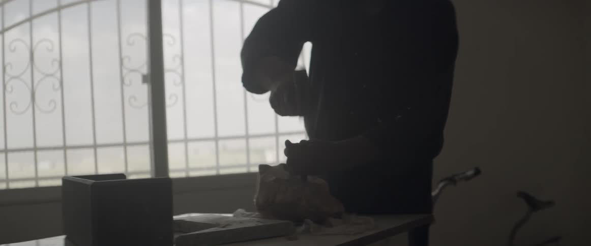 A man uses a hammer and chisel to shape a stone
