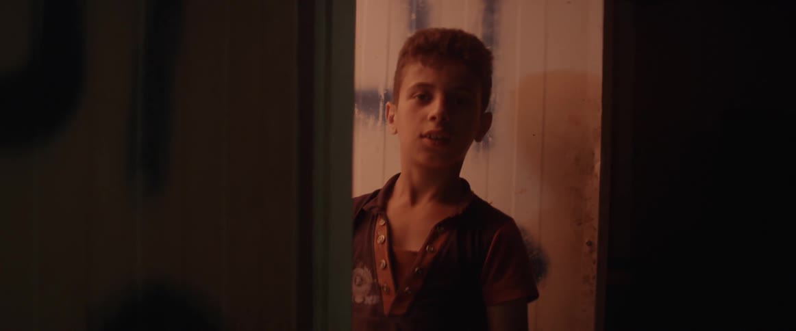 A boy stands in the doorway of a room