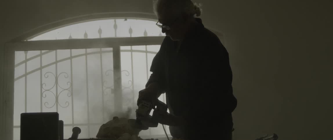 Man using a sander on a chunk of rock