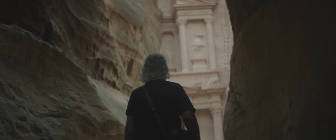 A man with a backpack walks along stone walls