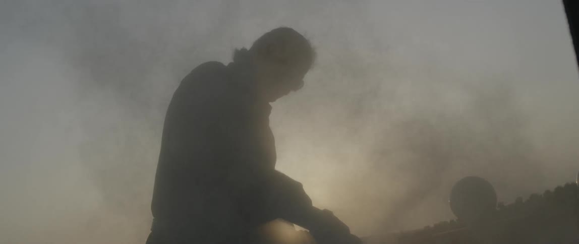 A man grinding on a large rock and making a lot of dust