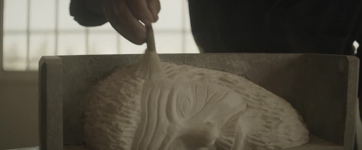 A man brushes dust off a sculpture