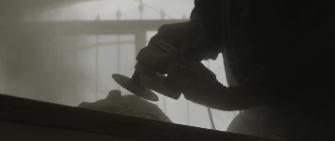 A man grinding a rock that is on top of a table