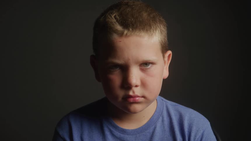 Close up portrait of a sad boy in a room