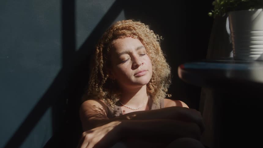 The woman is sitting by the window resting
