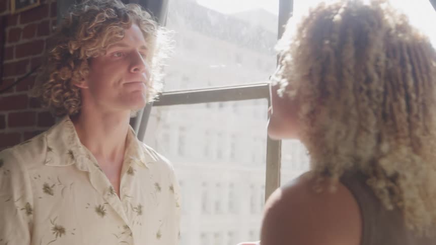 Two young people arguing near a window