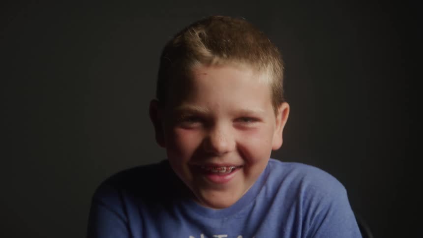 Happy young boy with braces wearing a blue shirt laughing