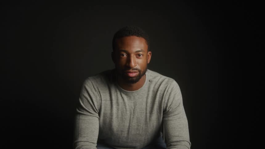 Man looking forward under soft lighting on dark background