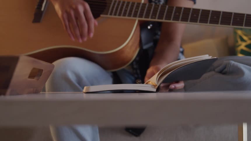 A guitar player opens the notebook and writes a note