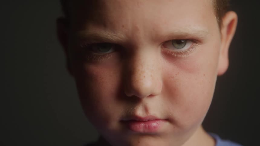 A young boy glares at the camera before slightly smiling