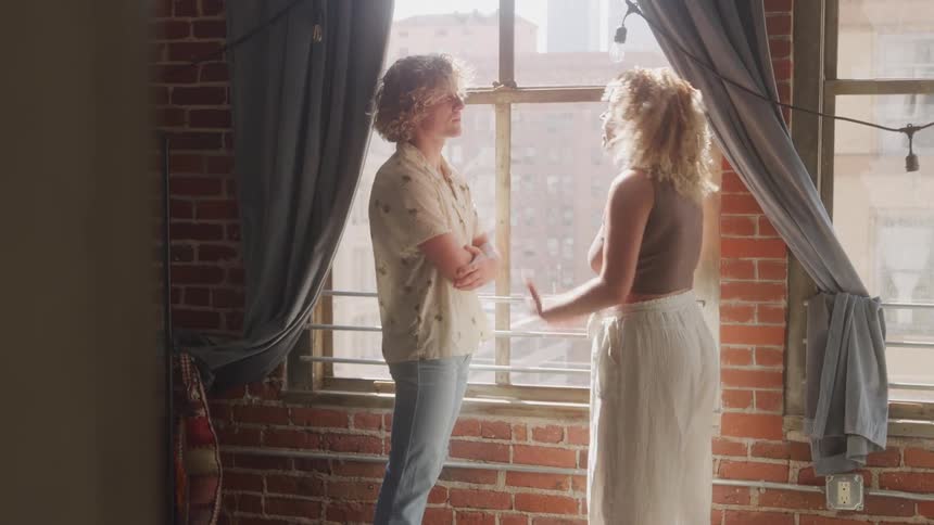 Woman arguing with a man next to a window of a building