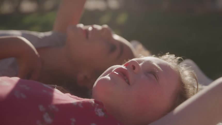 Two little girls lying in a backyard pointing upwards