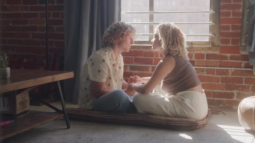 Couple sitting by a window holding hands