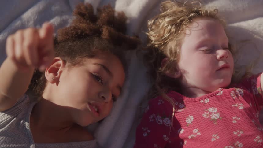 Two little girls lying down playing together
