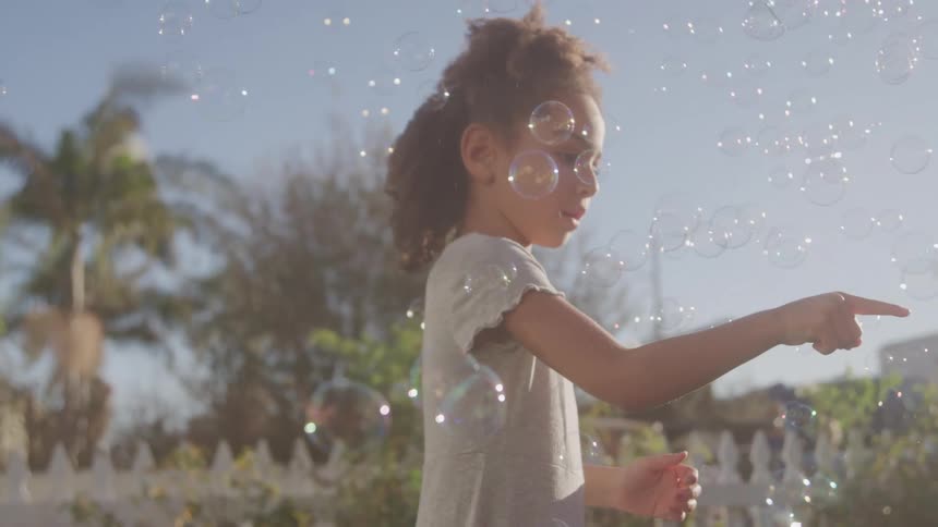 Two children playing with soap bubbles outdoors