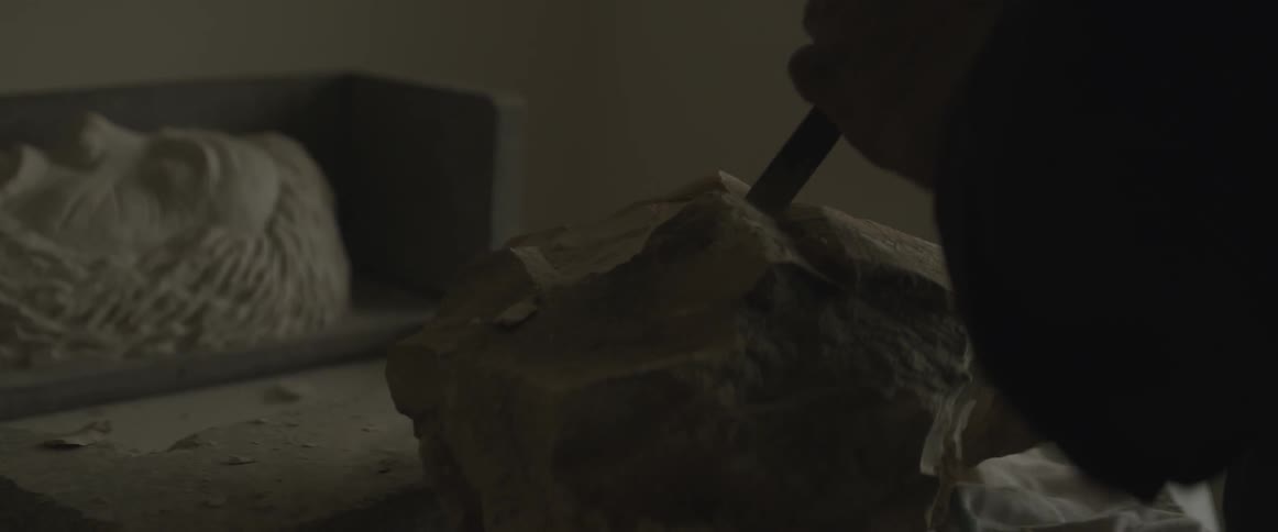 A man is hammering some stone