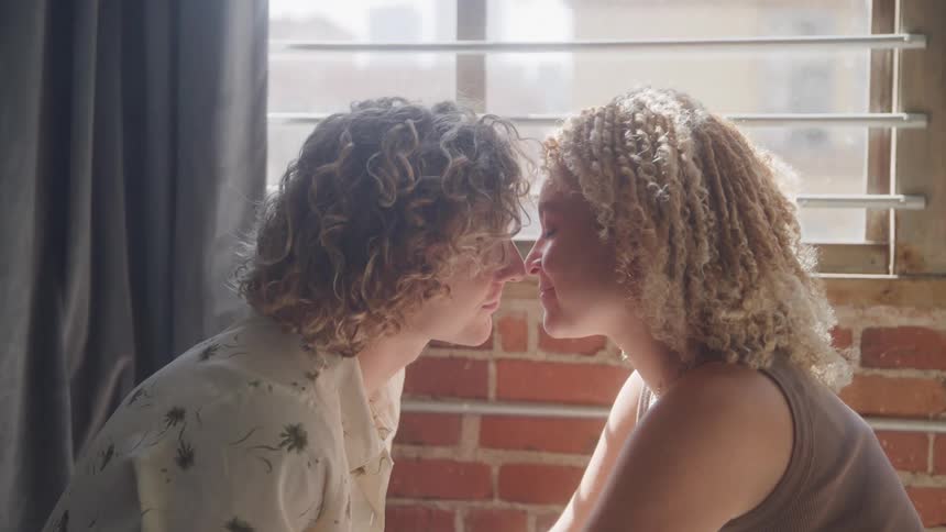 A couple sitting by the window kiss