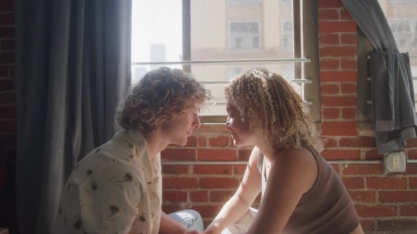 A couple kiss while sitting by the window